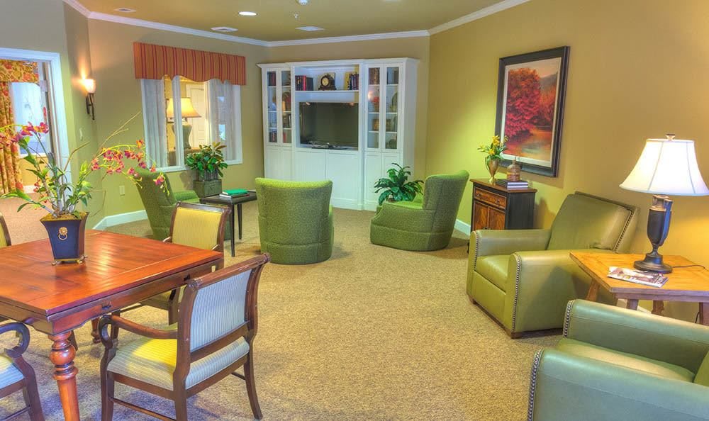 A cozy living room with comfortable armchairs, a table, decorative plants, and warm lighting.