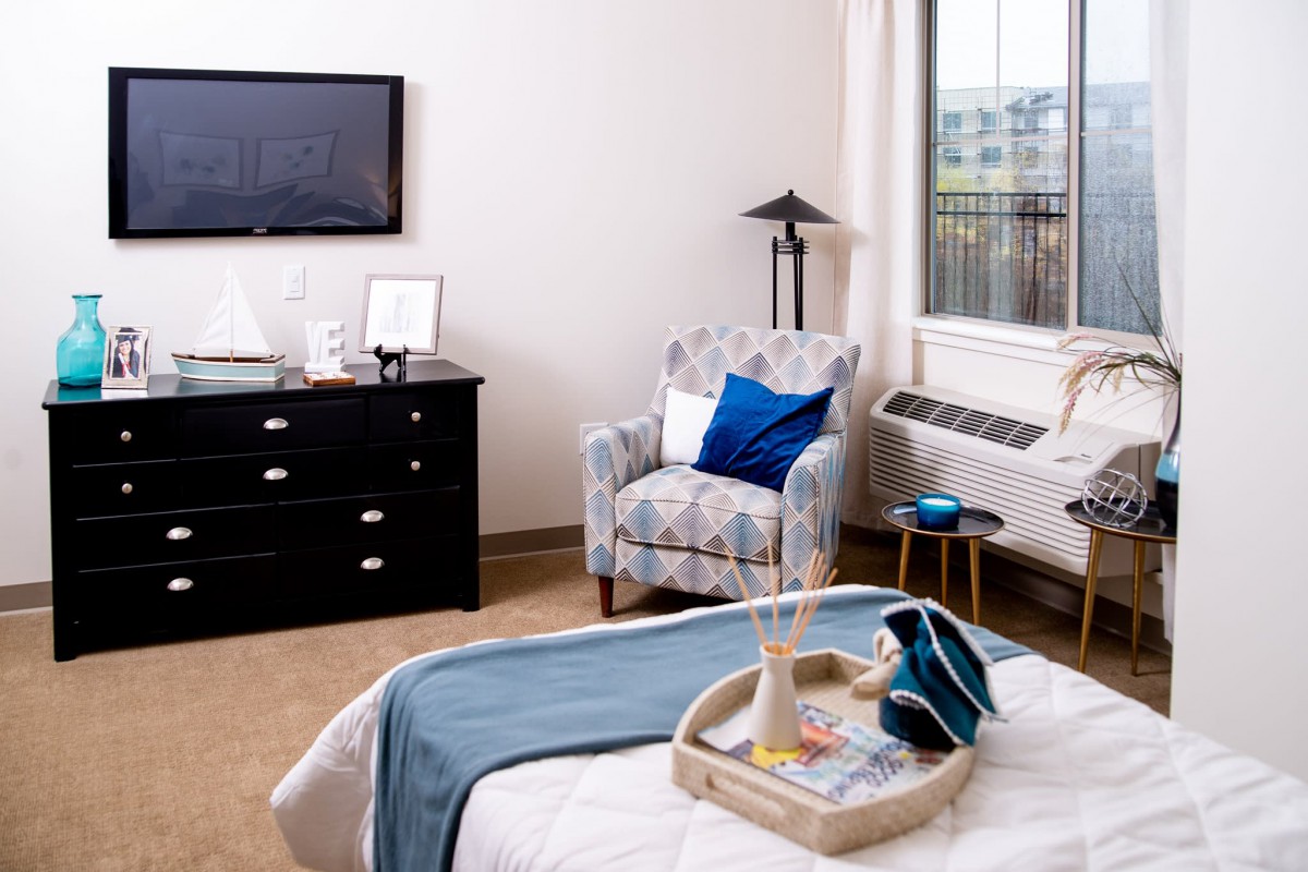 A cozy and modern bedroom featuring a comfortable armchair, sleek dresser, and stylish decor.
