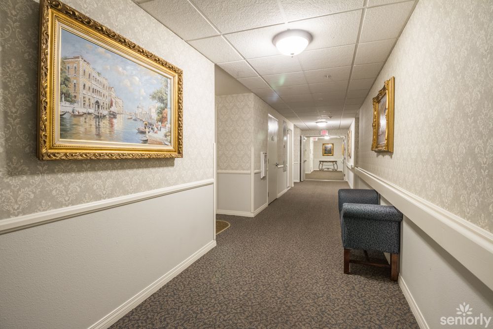 A well-lit hotel hallway featuring framed artwork and seating.