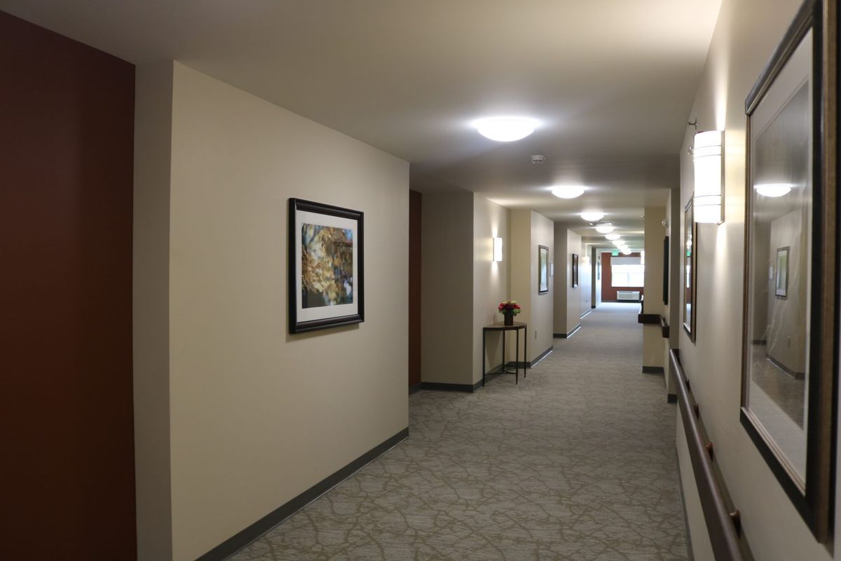 A well-lit hallway with artwork on the walls and a carpeted floor.