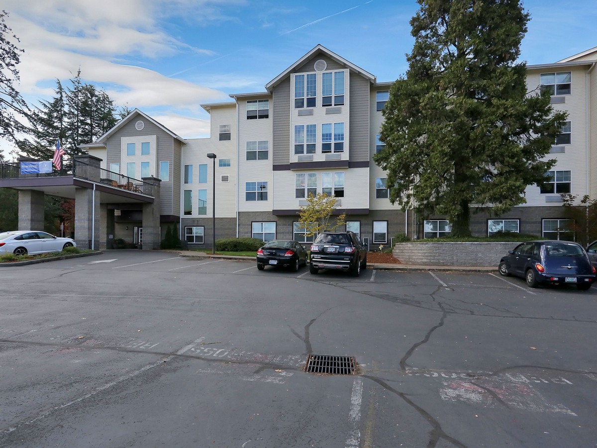 A modern apartment building with a parking lot and cars in a residential area.