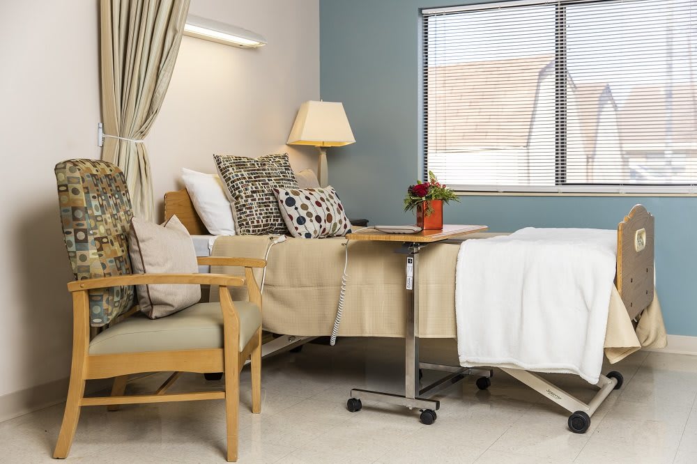 A comfortable and well-equipped hospital room with a bed, chair, and bedside table.