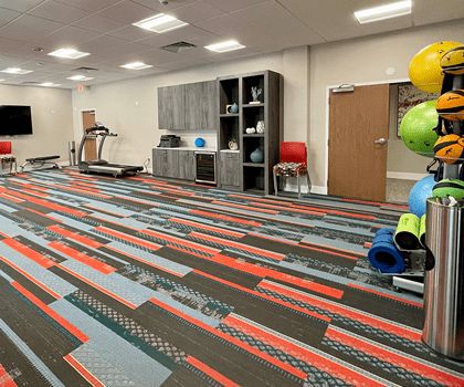 A modern gym with various fitness equipment, including a treadmill, yoga mats, and exercise balls.
