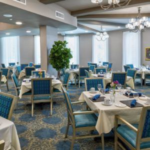 A spacious dining area with elegantly set tables and comfortable seating, featuring chandeliers and a stylish decor.