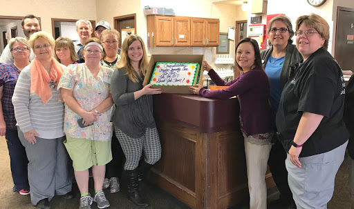A team gathering to celebrate a special occasion with cake.