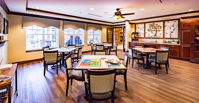 A modern dining area featuring several tables and chairs with large windows and wooden flooring.