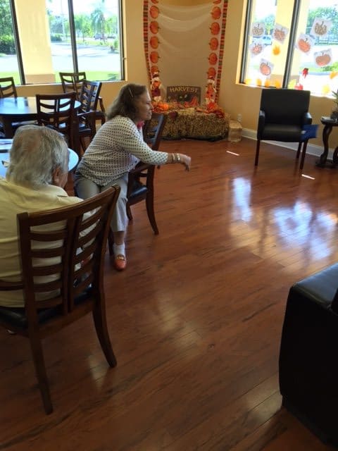 Elderly individuals engaging in an indoor activity on a wooden floor.
