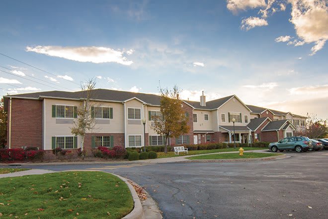 A suburban residential apartment complex with a driveway and landscaped surroundings.