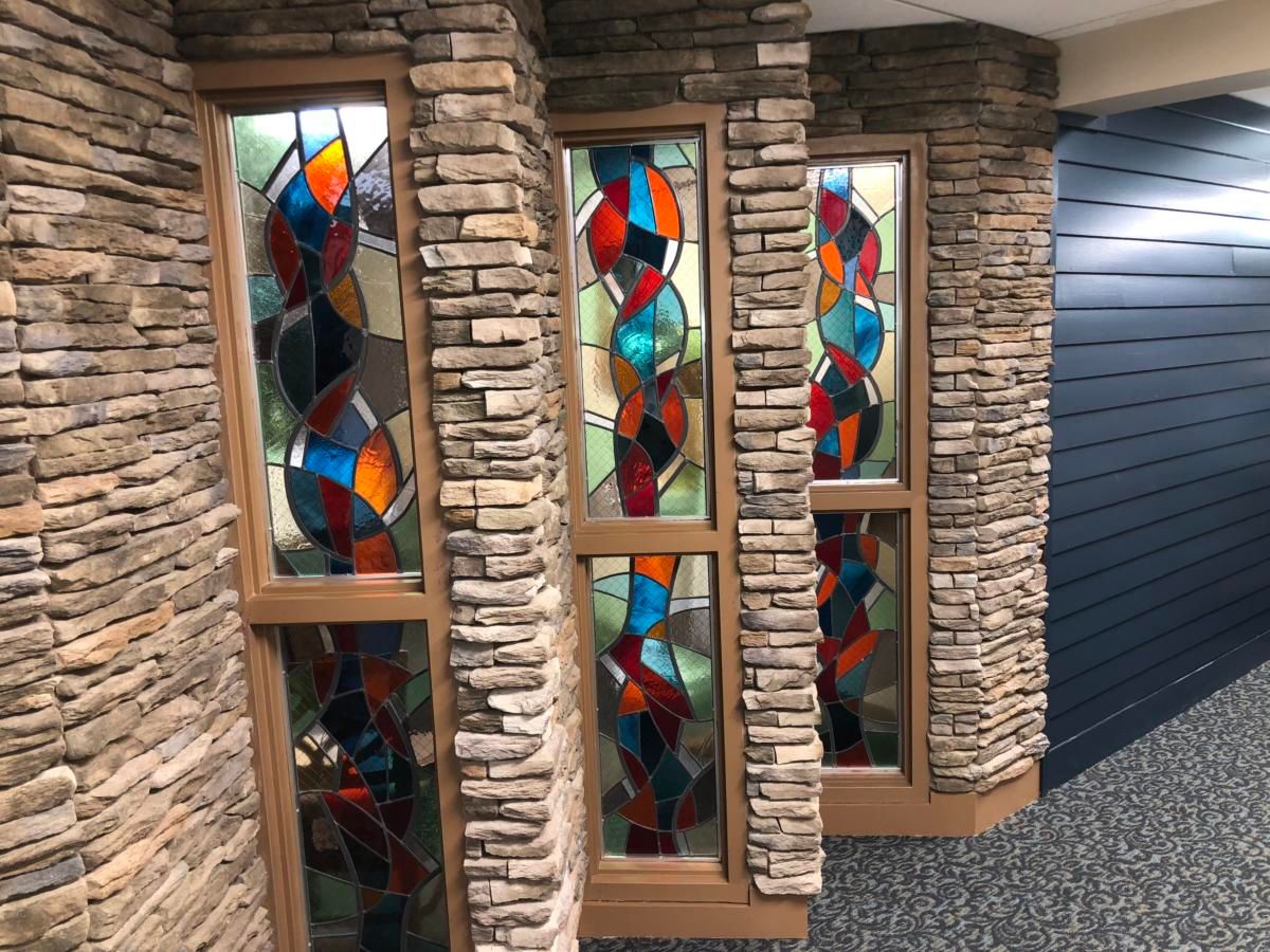 A decorative interior featuring colorful stained glass windows set within a stone wall.