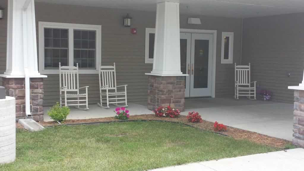 A cozy porch with rocking chairs and colorful flowers near the entrance.