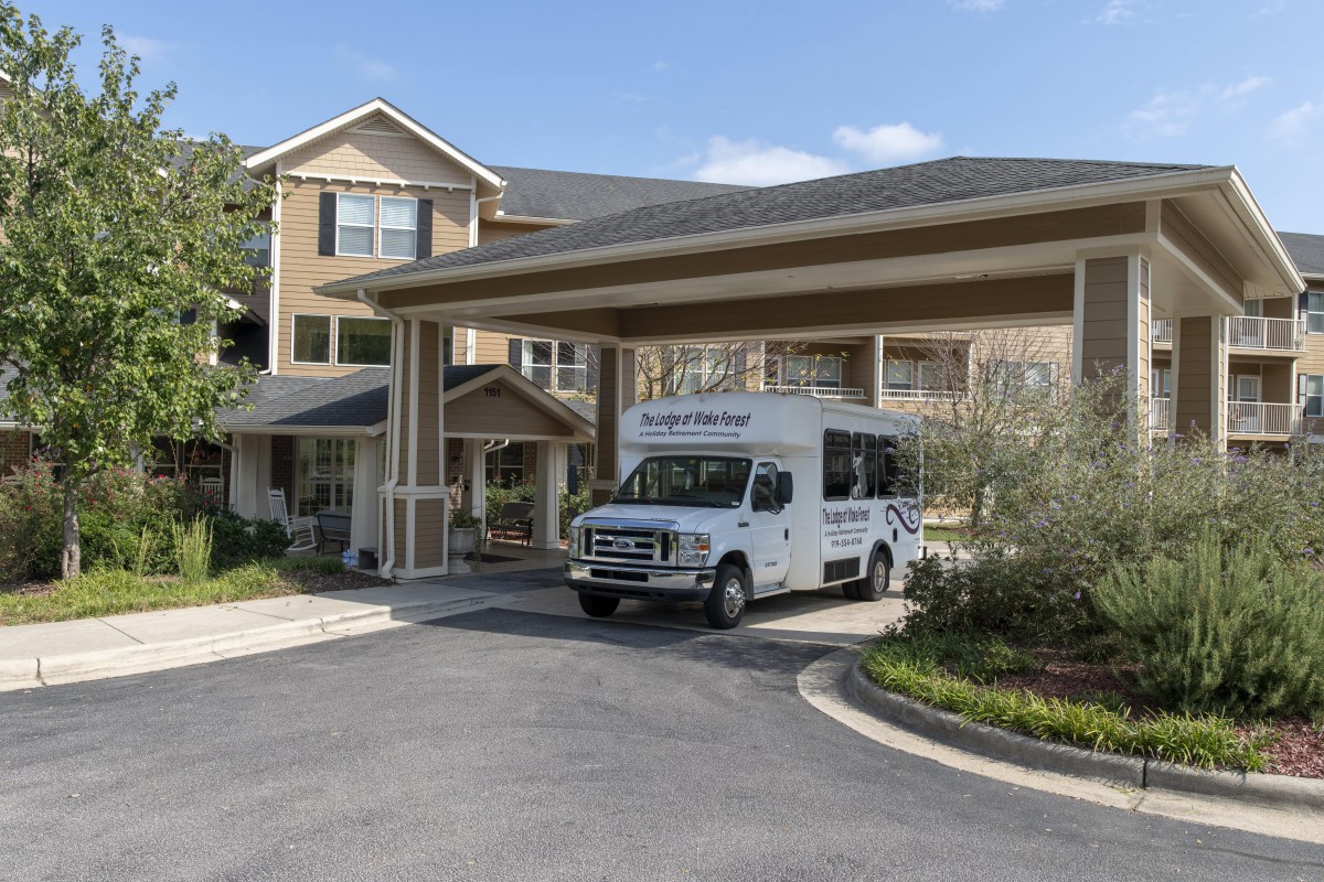 A van parked under the entrance of a building with a covered walkway.