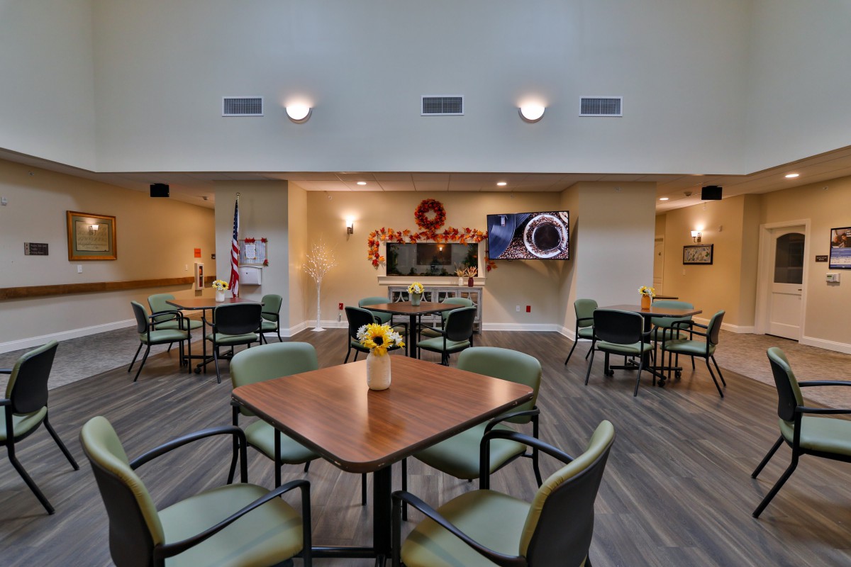 A cozy community dining area with tables set for social gatherings, adorned with decorative elements and a TV for entertainment.