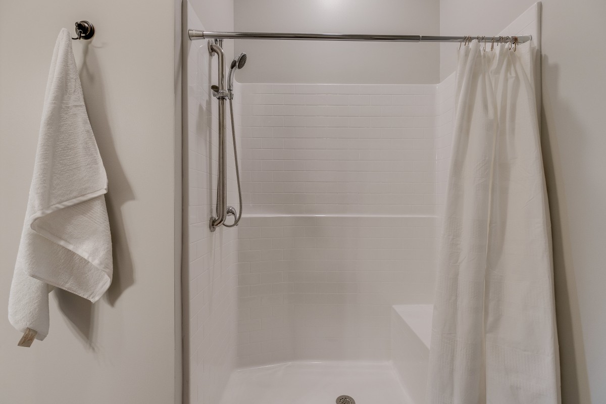 A bathroom with a shower area featuring a curtain and towel.