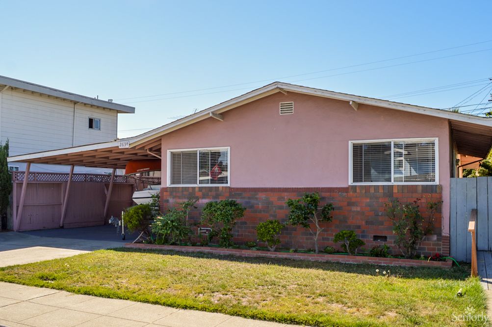 A single-story suburban house with a front yard on a sunny day.