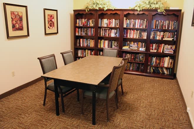 A cozy library corner with bookshelves, a table, and chairs for reading and study.