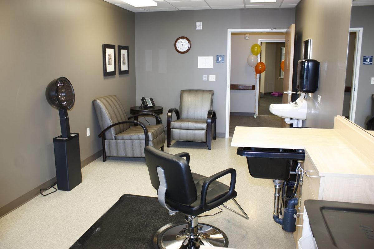 A hair salon interior featuring a barber chair, waiting area, and sink.