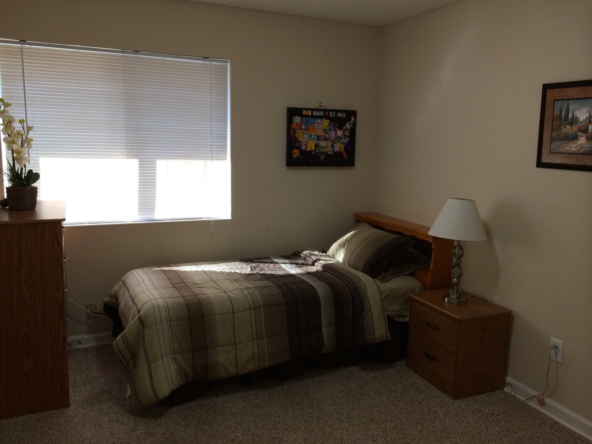 A minimalist bedroom with a single bed, nightstand, and lamp.