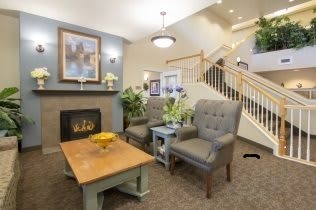 A cozy living room with a fireplace, comfortable seating, and stairs leading to the upper floor.