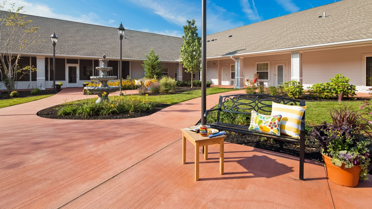 A peaceful courtyard with a bench and fountain surrounded by greenery.