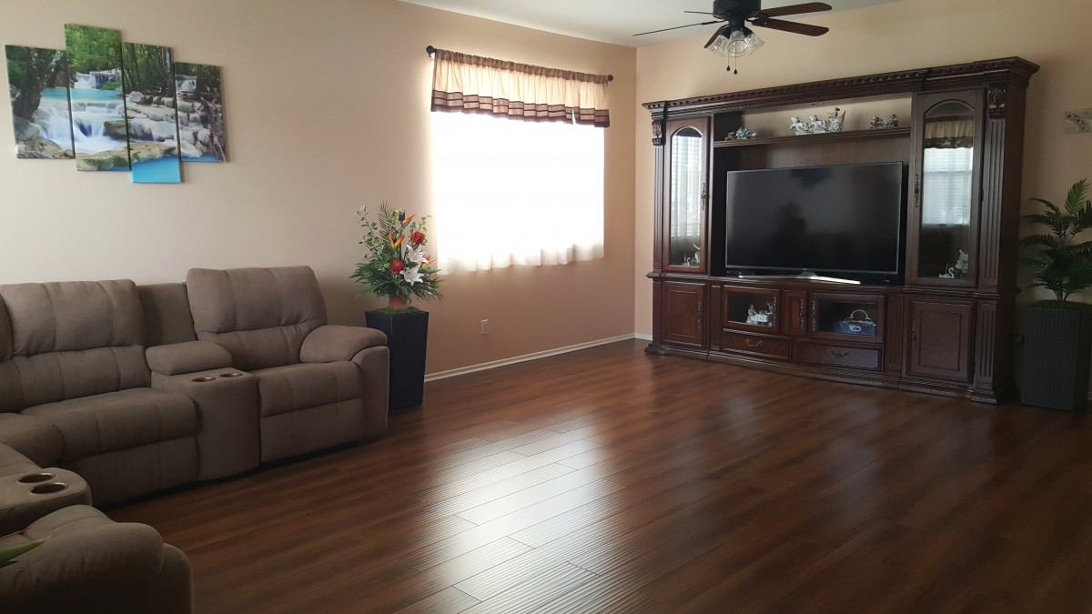 A cozy living room with a recliner, hardwood floors, and entertainment center featuring a large television.