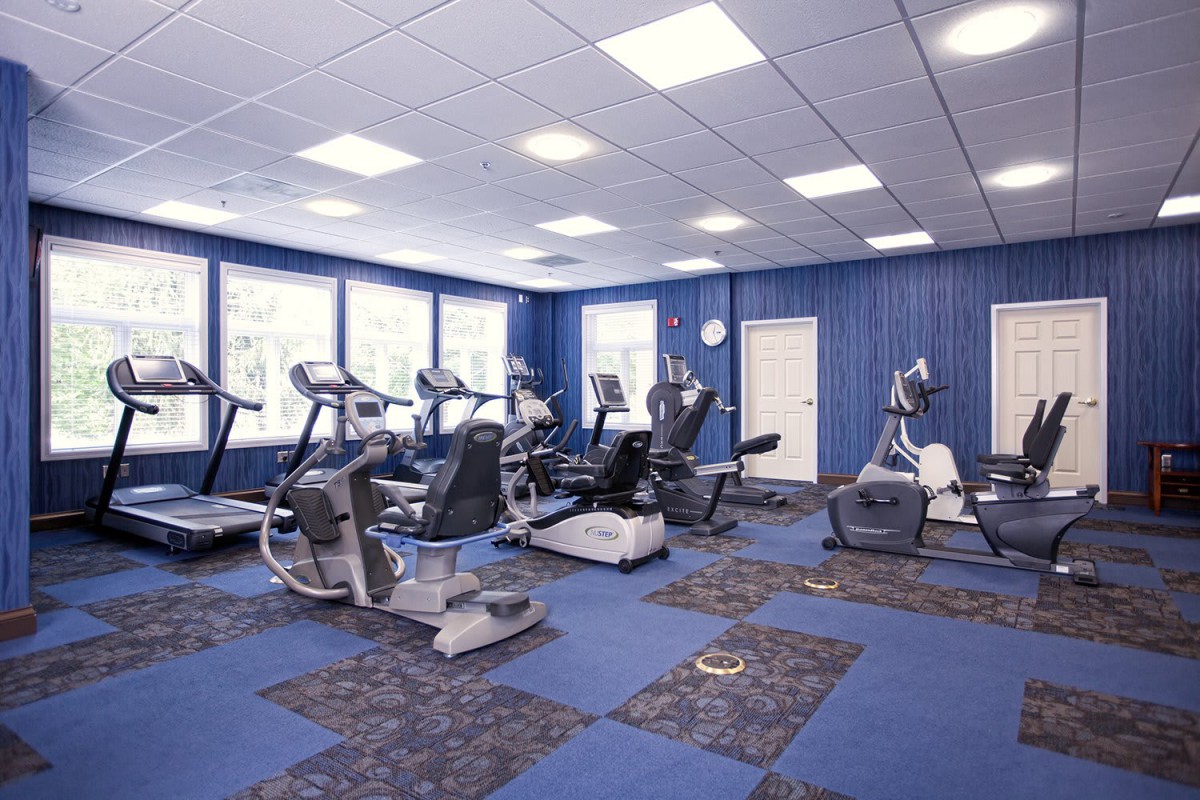 A well-lit gym featuring various exercise machines, including treadmills and cardio equipment.