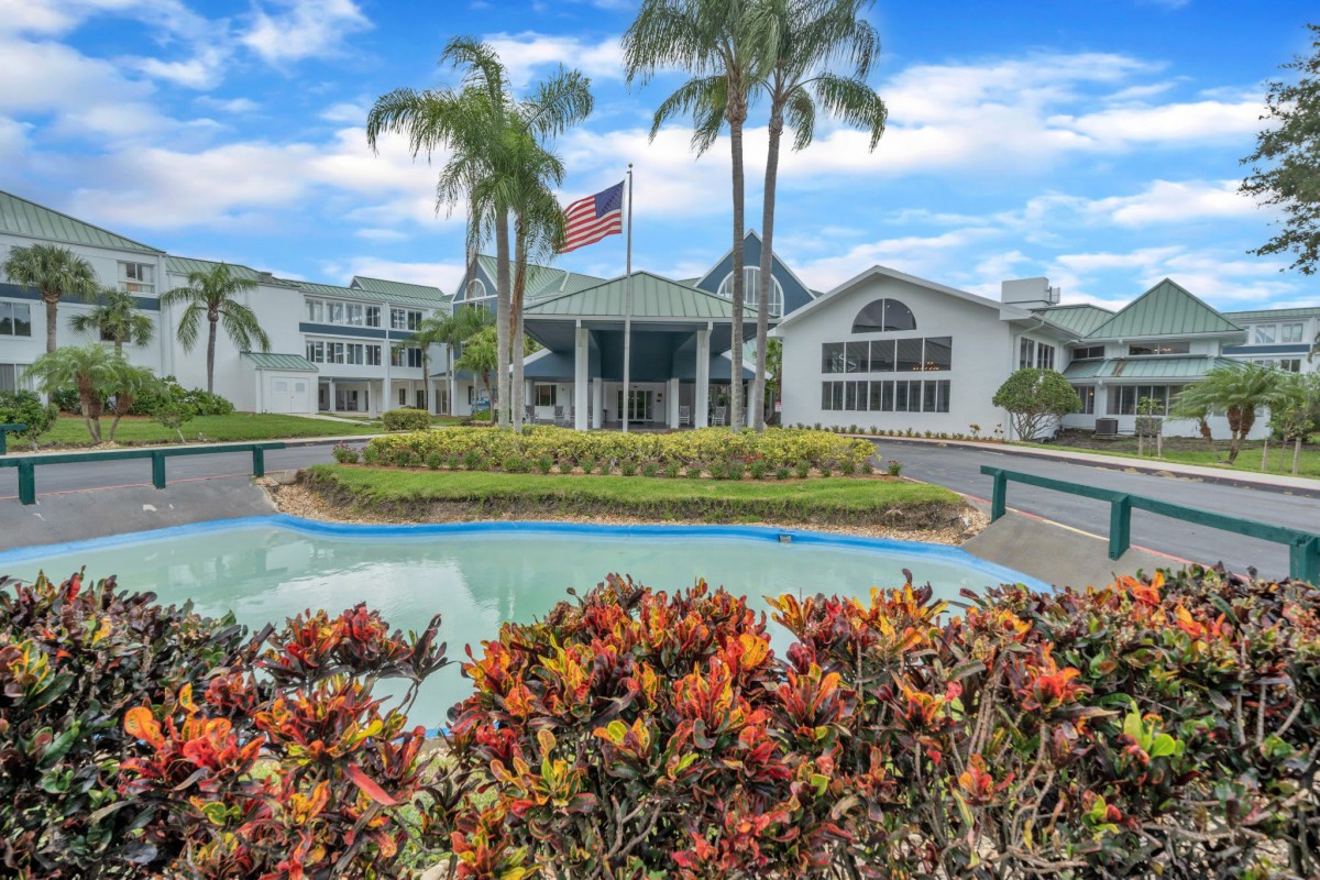 A welcoming hotel entrance surrounded by lush tropical landscaping and palm trees.