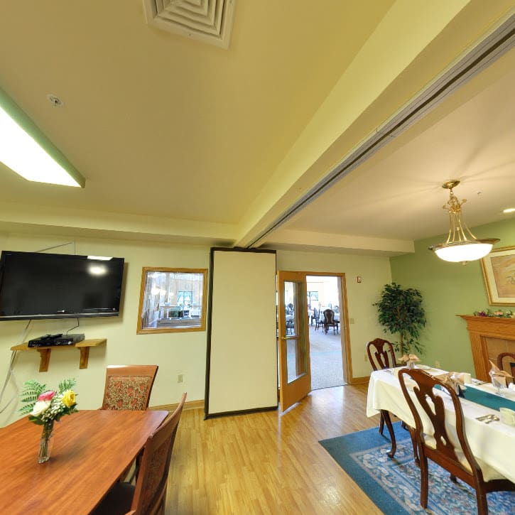 A cozy dining room with elegant furniture and a television on the wall.