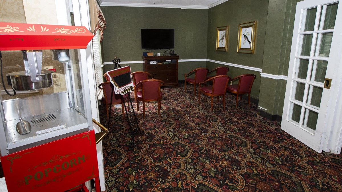 A cozy room with red chairs, a wall-mounted television, and decorative artwork on green walls.