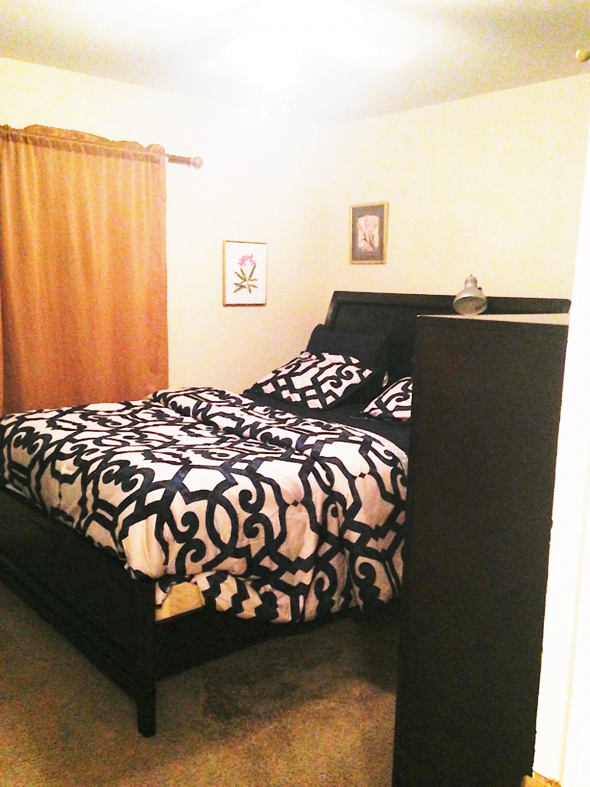 A cozy bedroom with patterned bedding and warm-toned curtains.