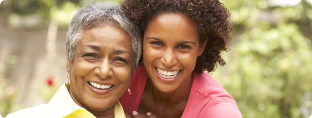 Two women smiling warmly outdoors.