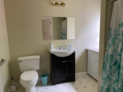 A clean bathroom with a toilet, sink, and mirror.