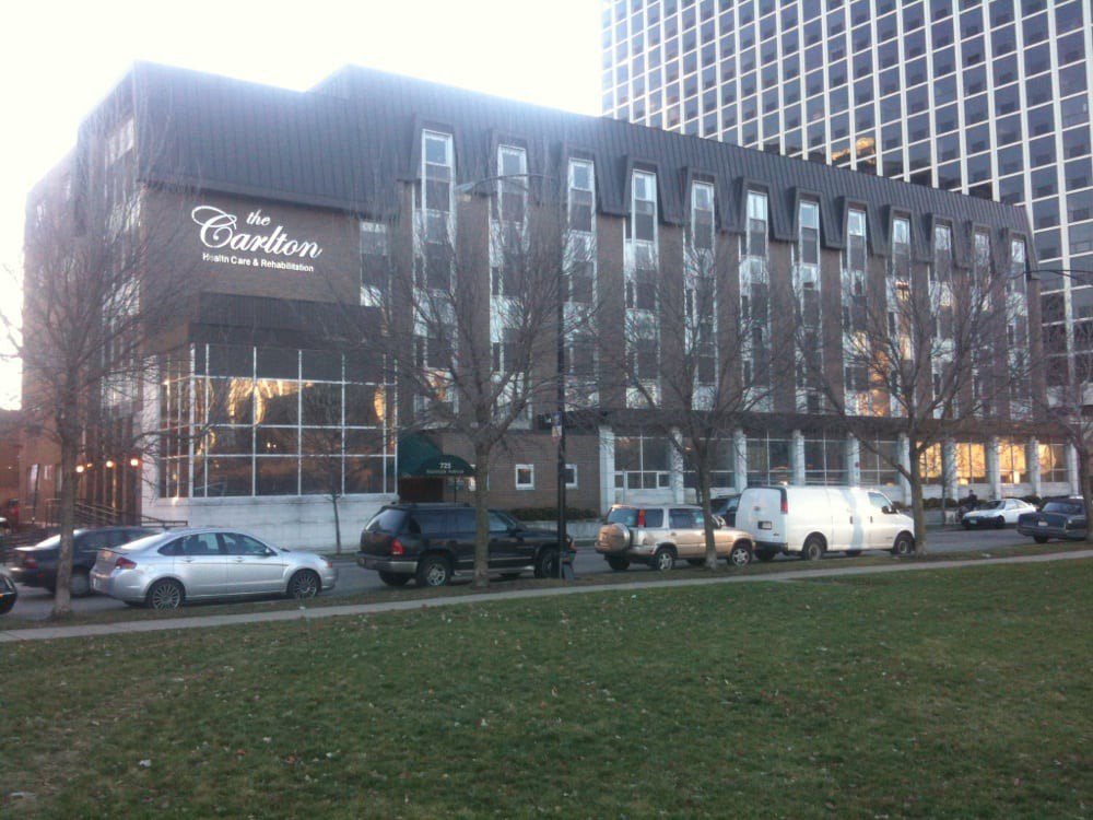 A view of a hotel building with cars parked in front during the day.
