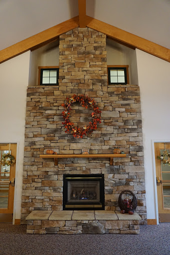 A cozy living room featuring a stone fireplace adorned with a seasonal wreath and wooden beams enhancing the rustic charm.