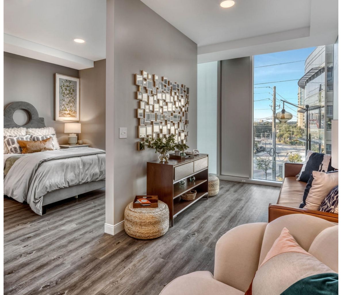 A modern bedroom with stylish decor, featuring wood flooring and abundant natural light.