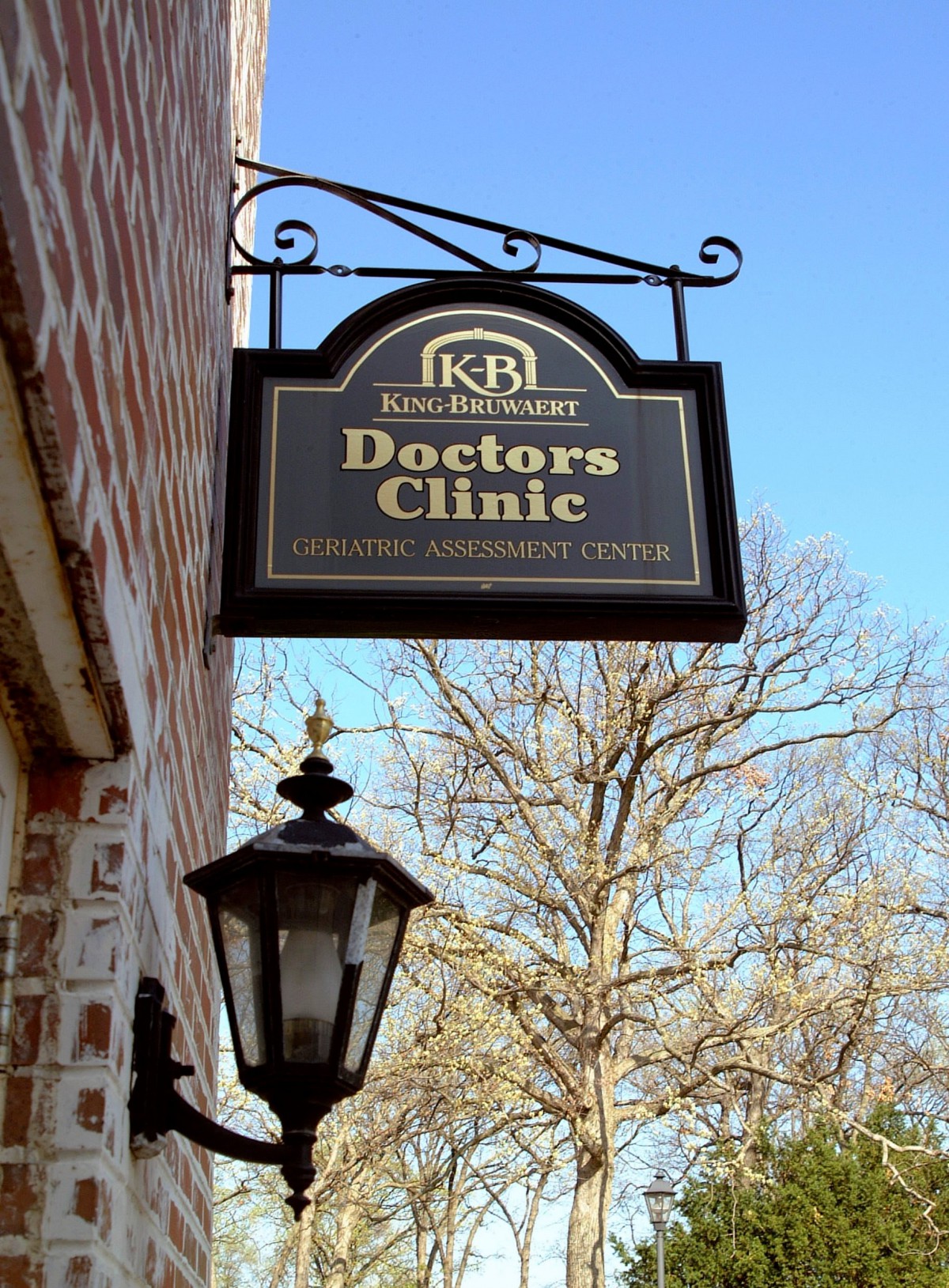 A sign for a doctor's clinic hanging outside a brick building.