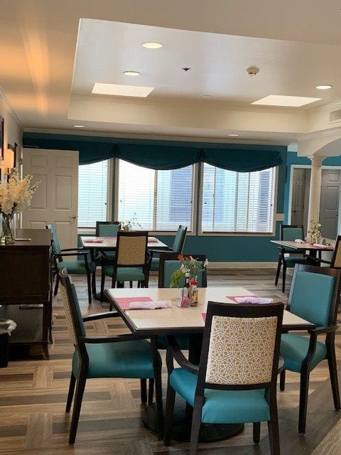 A well-lit dining room with neatly arranged tables and chairs.