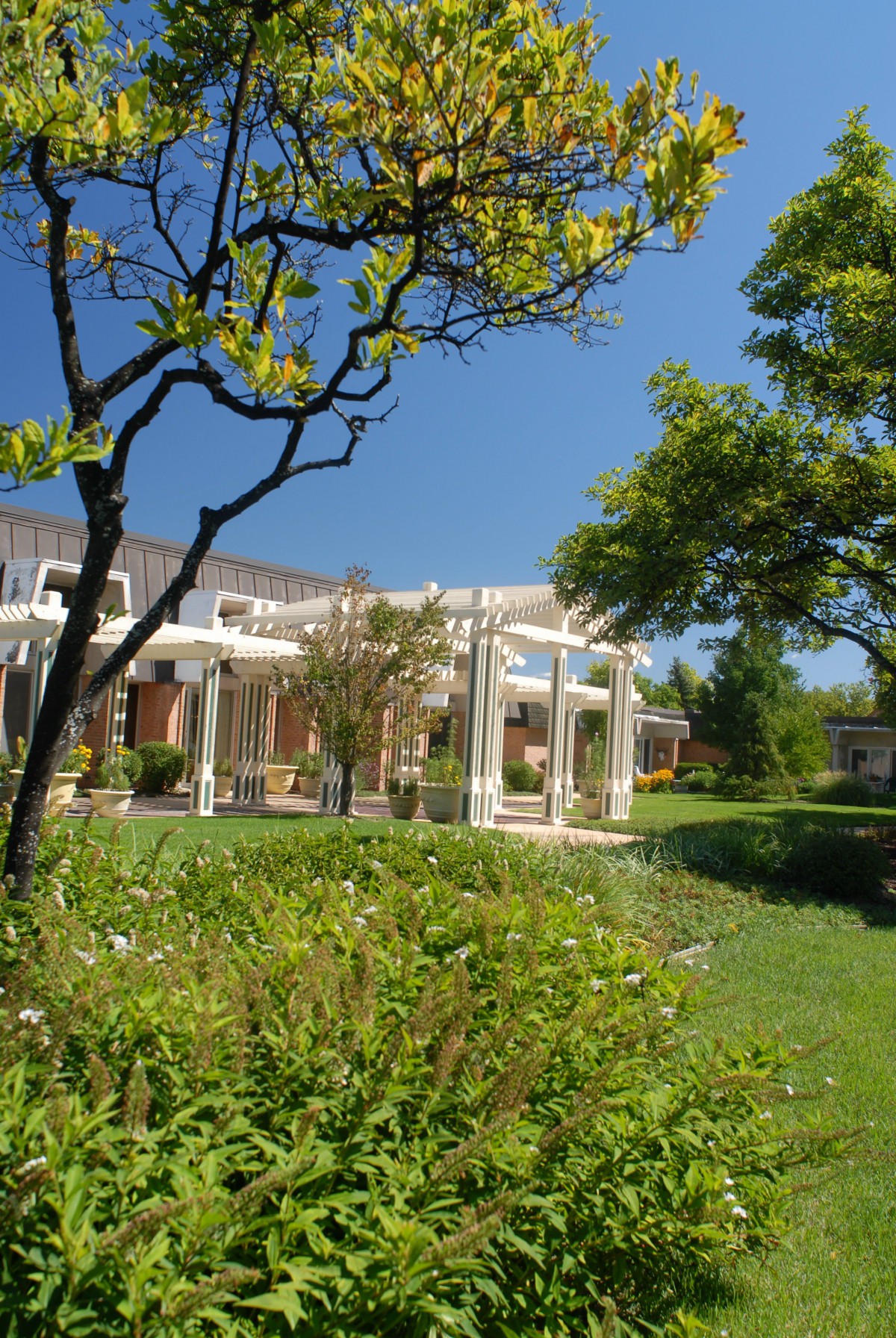 A scenic view of a building surrounded by lush gardens and trees under a clear blue sky.