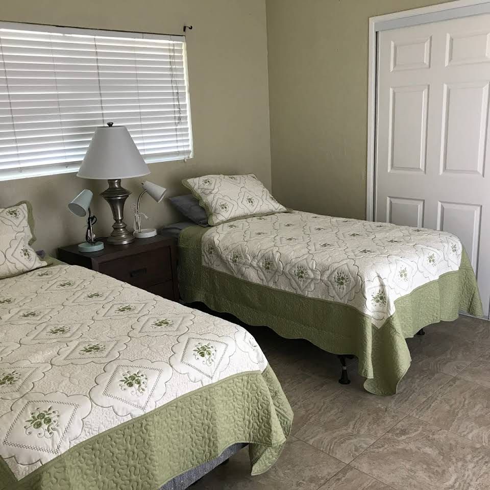 A cozy bedroom with two twin beds, a nightstand, and a lamp.