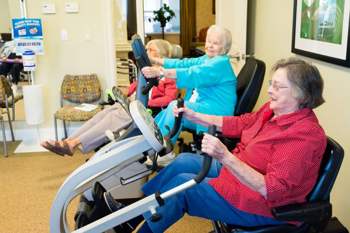 Seniors engaging in indoor fitness activities on exercise machines.