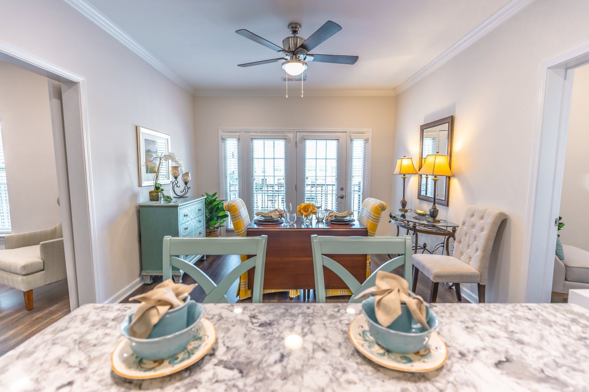 A modern dining room with a well-set table, featuring elegant decor and ample natural light.