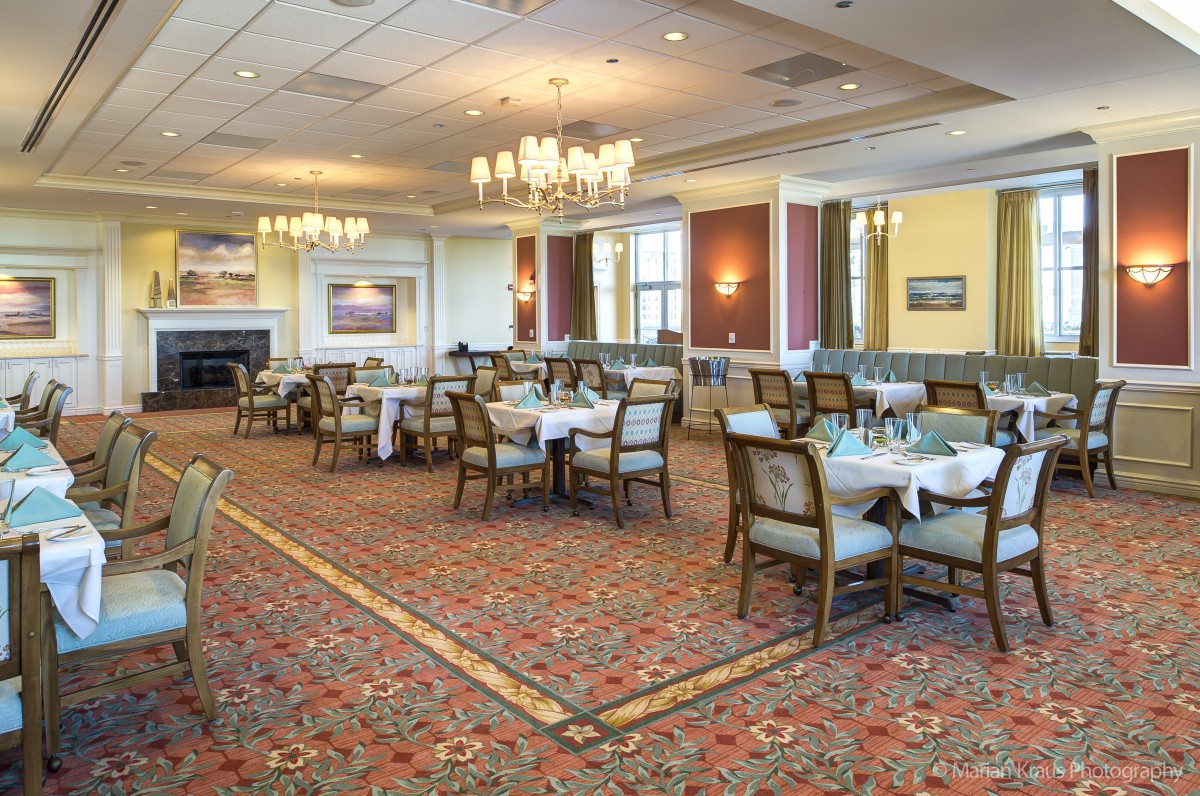 An elegant dining room with neatly arranged tables and chandeliers.
