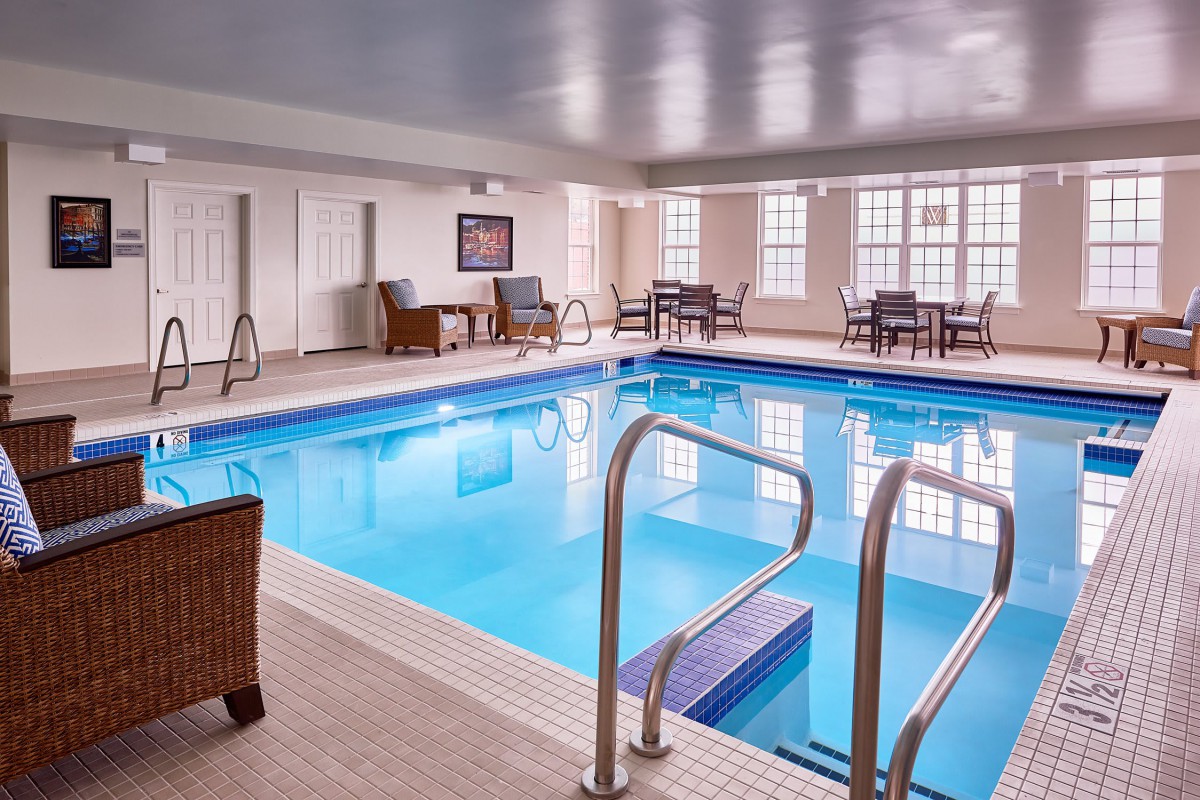 An inviting indoor swimming pool area with seating and tables for relaxation.