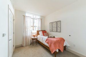 A cozy bedroom with a single bed and natural light from a large window.