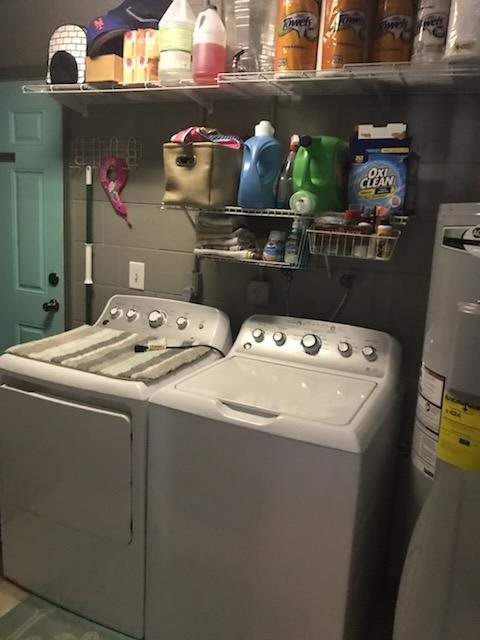 A cozy laundry room featuring a washer and dryer with shelves stocked with cleaning supplies.