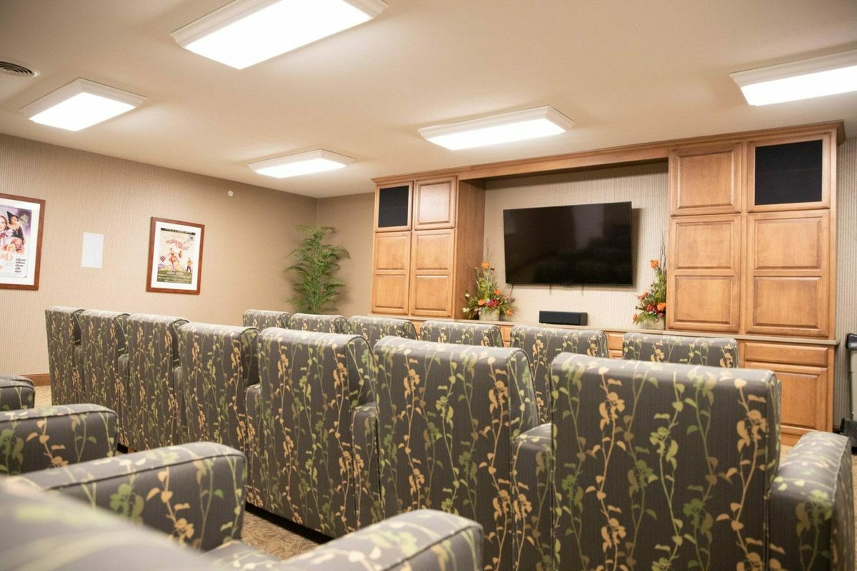 A cozy home theater room with patterned seating facing a large television.