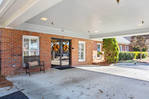 A welcoming entrance featuring a brick facade, decorative door wreaths, and a comfortable bench.