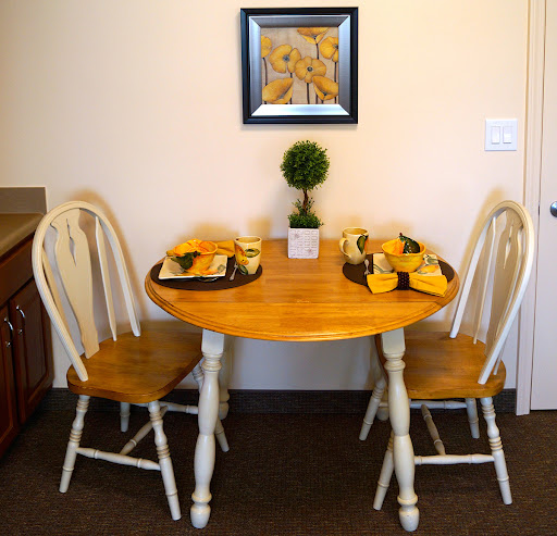 A cozy dining setup featuring a round wooden table with two chairs, decorated for a casual meal.