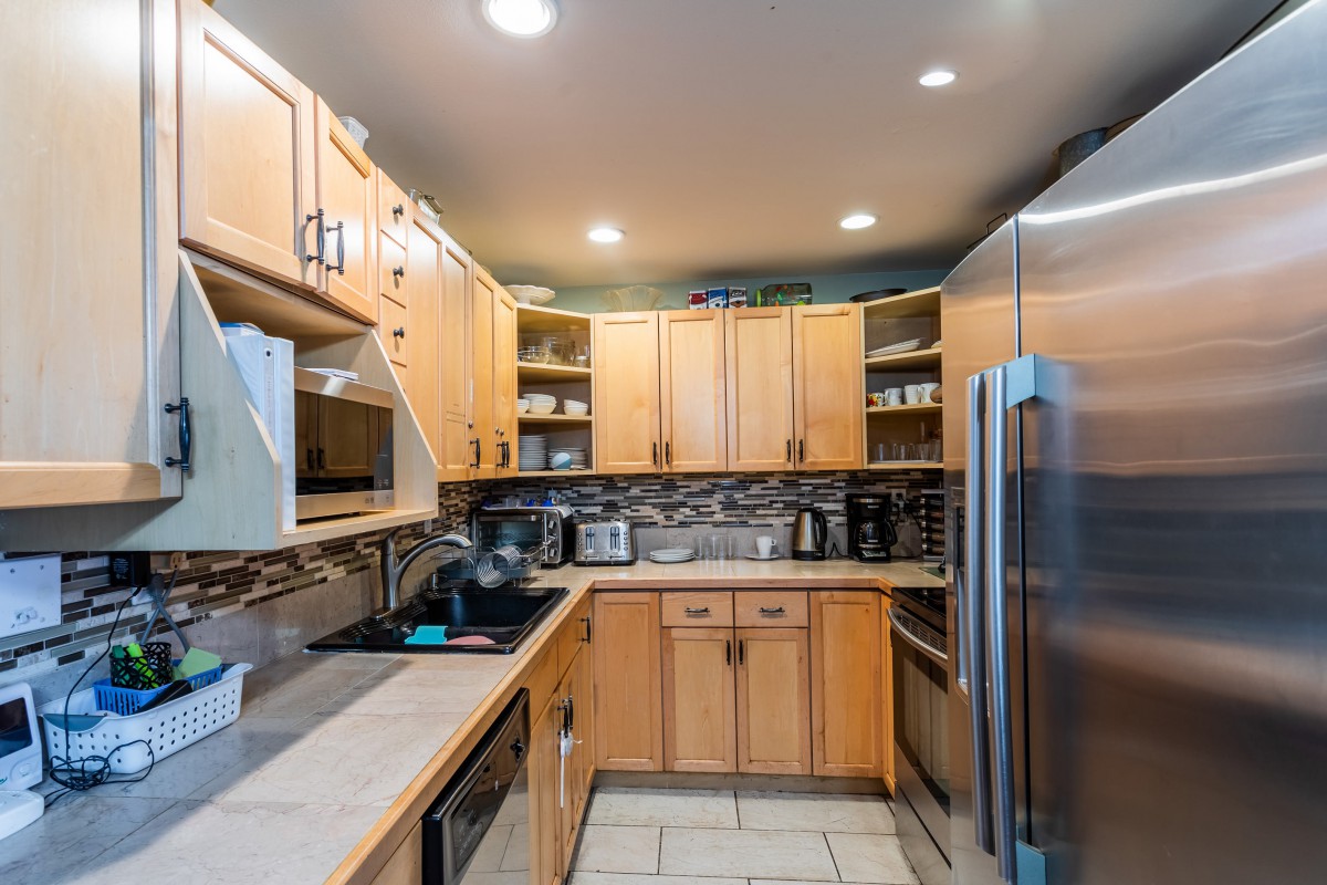 A modern kitchen with wooden cabinets, stainless steel appliances, and ample lighting.