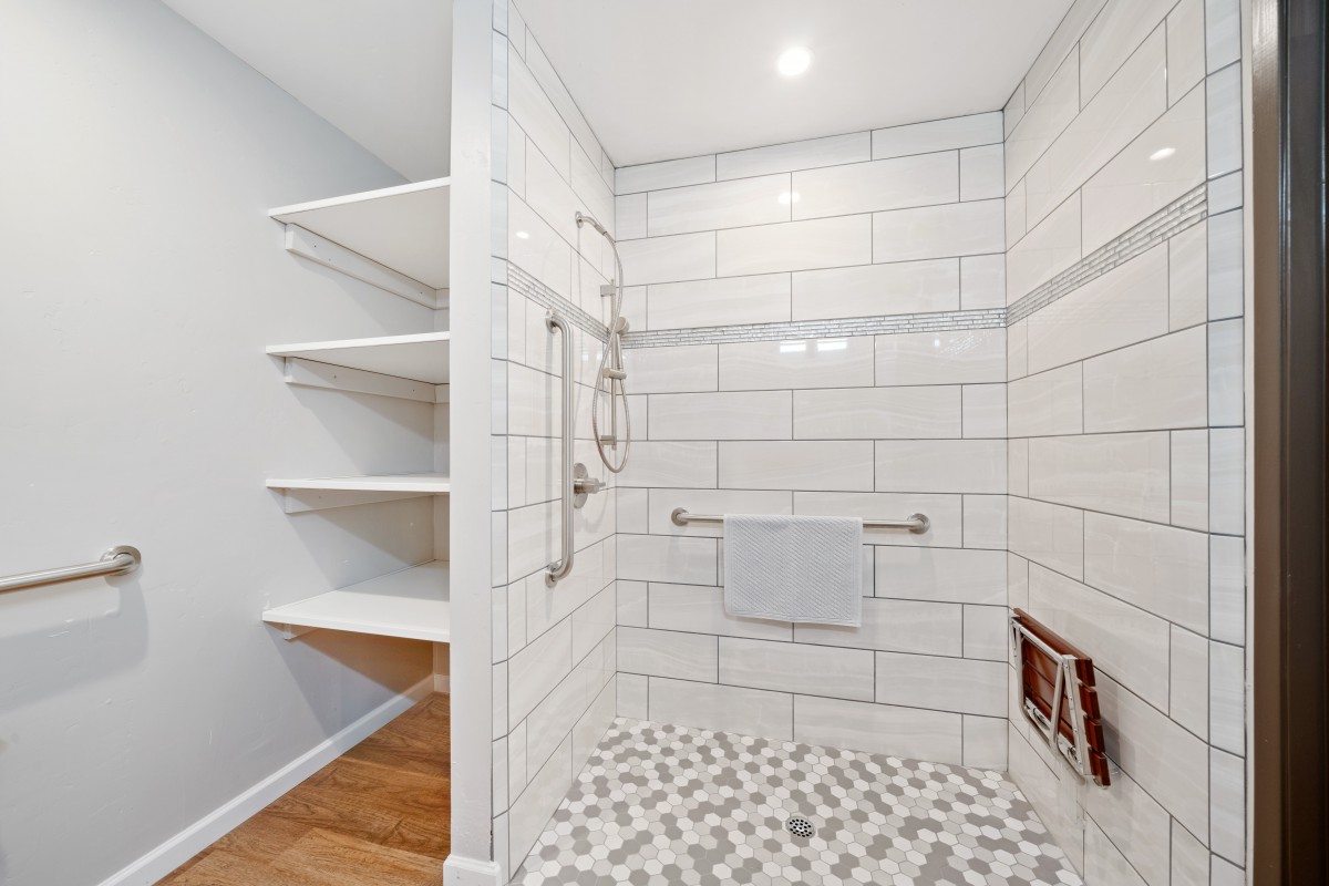 A modern bathroom with a tiled shower and open shelving.