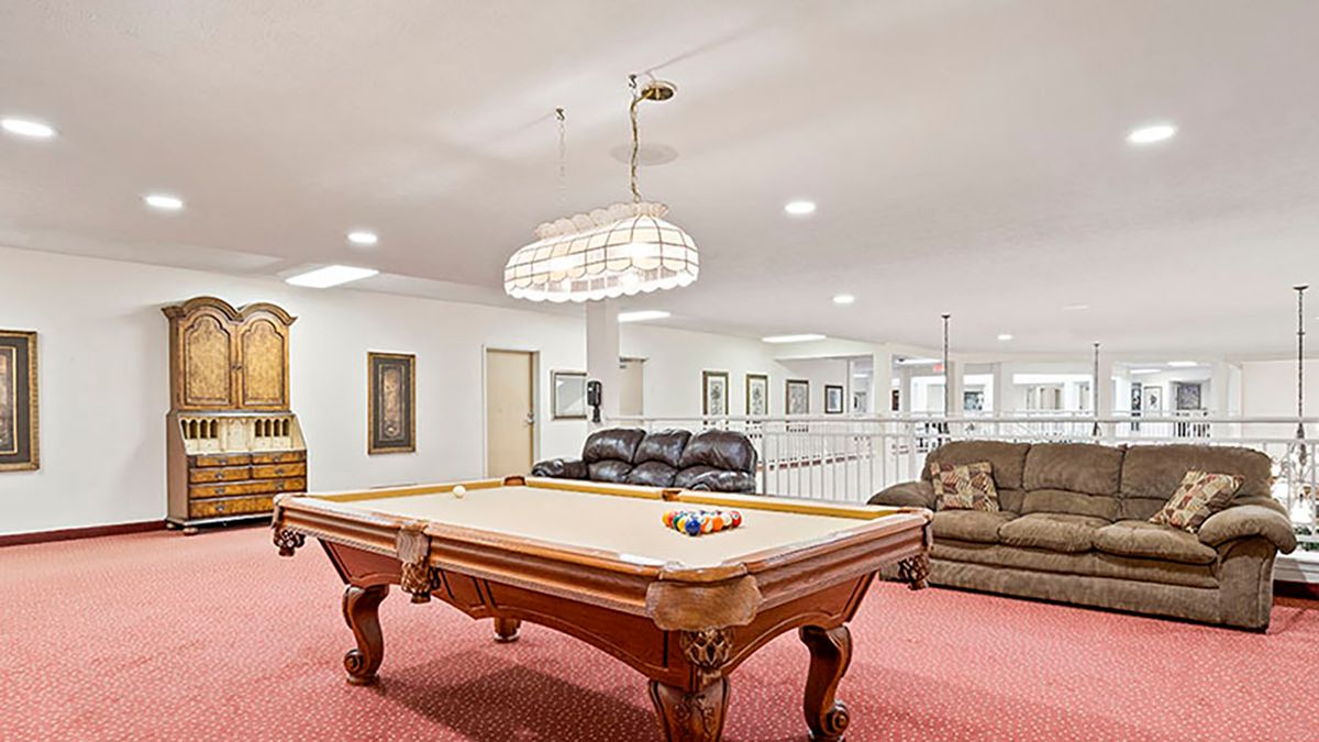 A spacious game room featuring a pool table and comfortable seating.